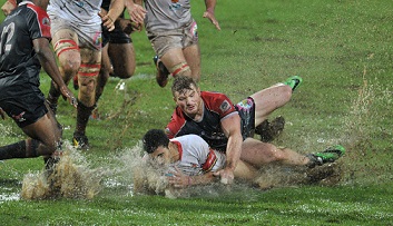 FNB NMMU's Christopher Cloete tackles FNB Tuks's Jade Stighling during their rain-soaked FNB Varsity Cup clash in Pretoria on Monday night. Photo: Wessel Oosthuizen/SASPA